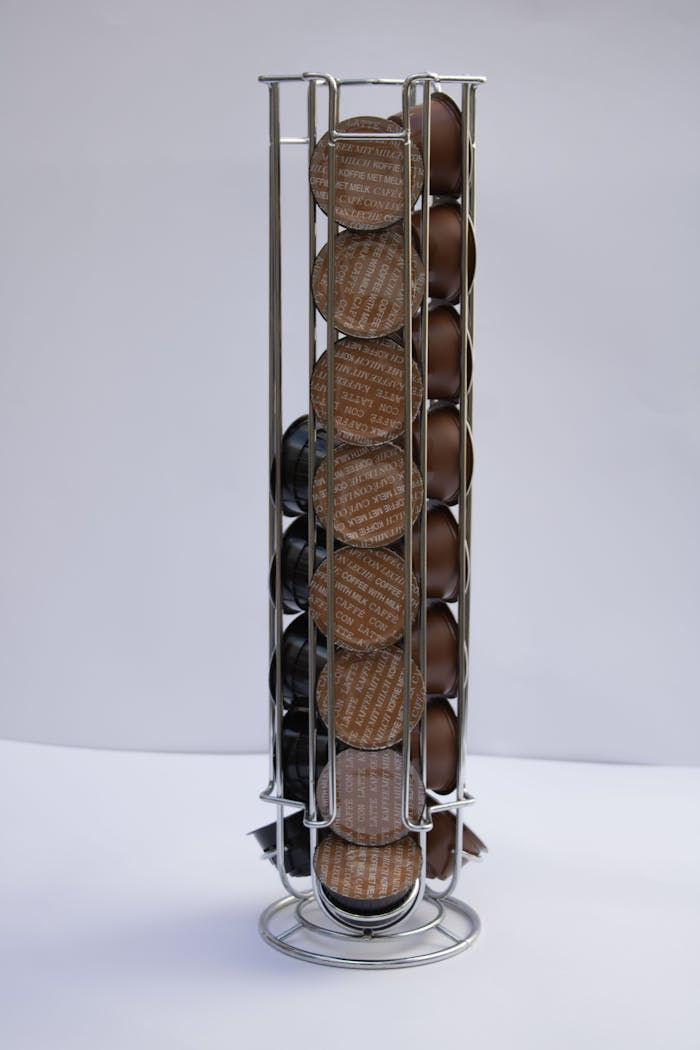 Vertical shot of a metal rack holding brown coffee capsules, isolated on white.