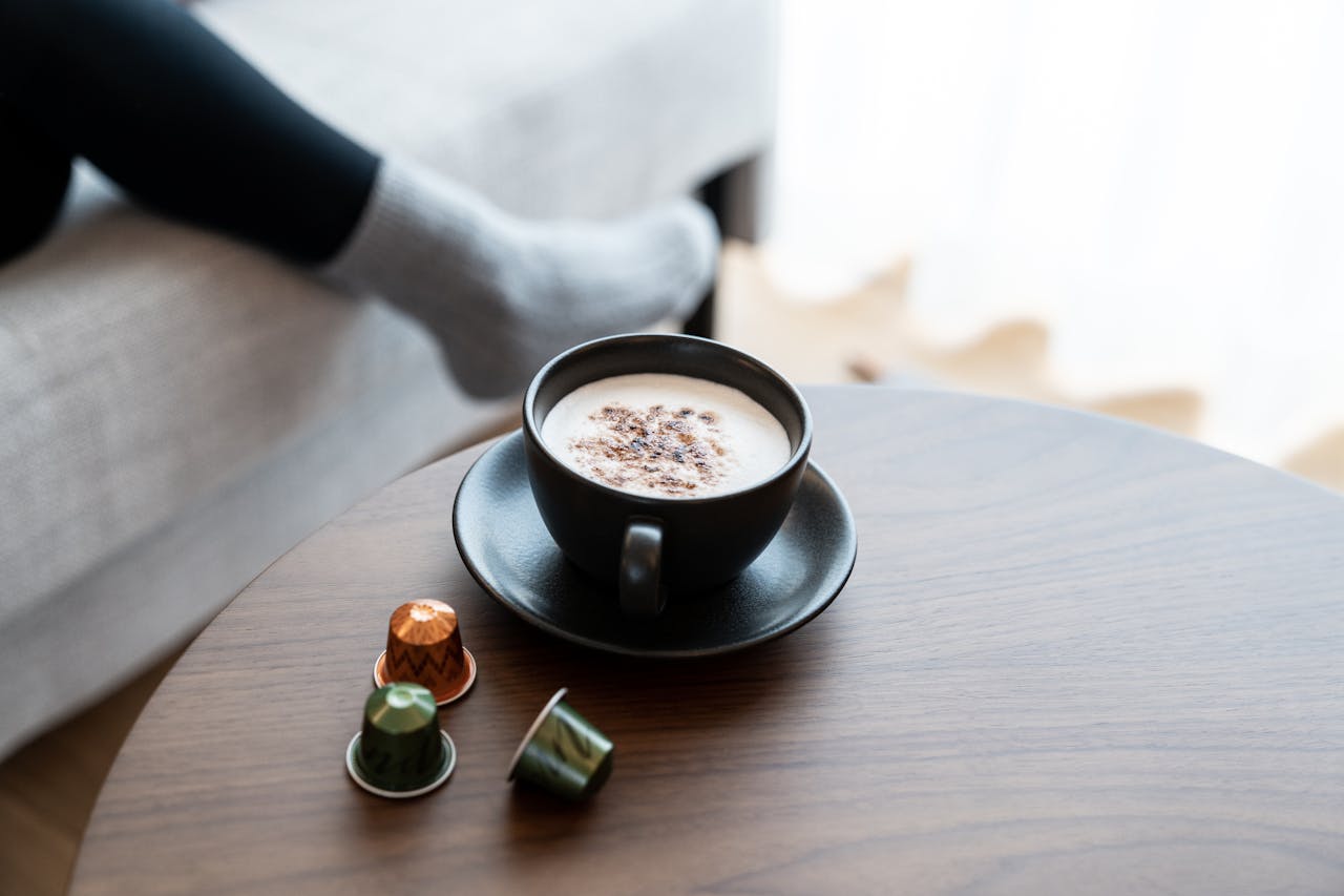 A warm cup of coffee on a wooden table with a cozy backdrop, perfect for relaxation.