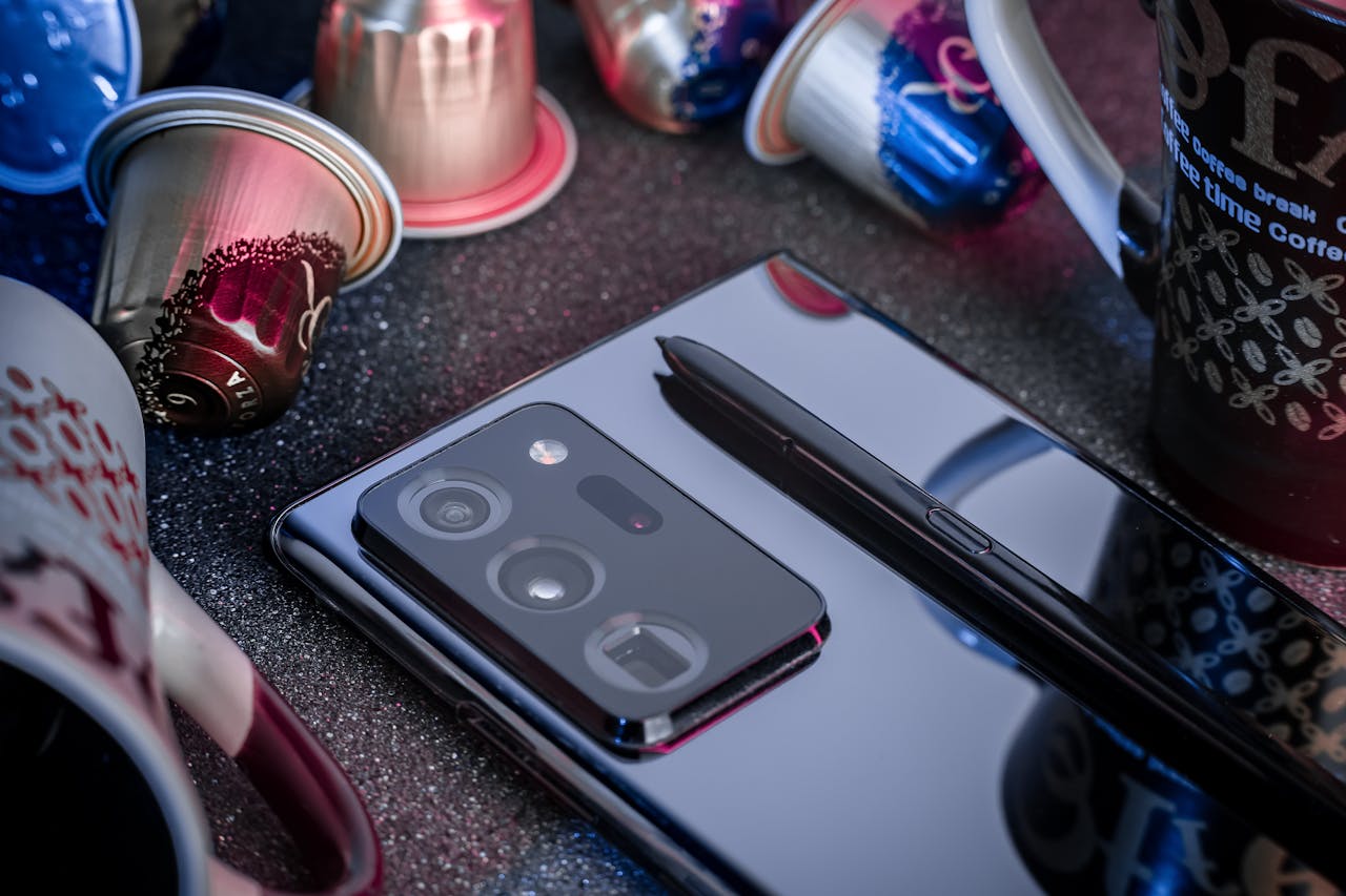 Stylish smartphone and pen beside coffee capsules; modern technology and lifestyle concept.