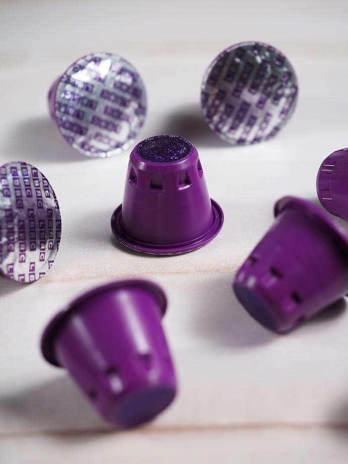 Close-up of purple sealed coffee capsules arranged on a marble surface.