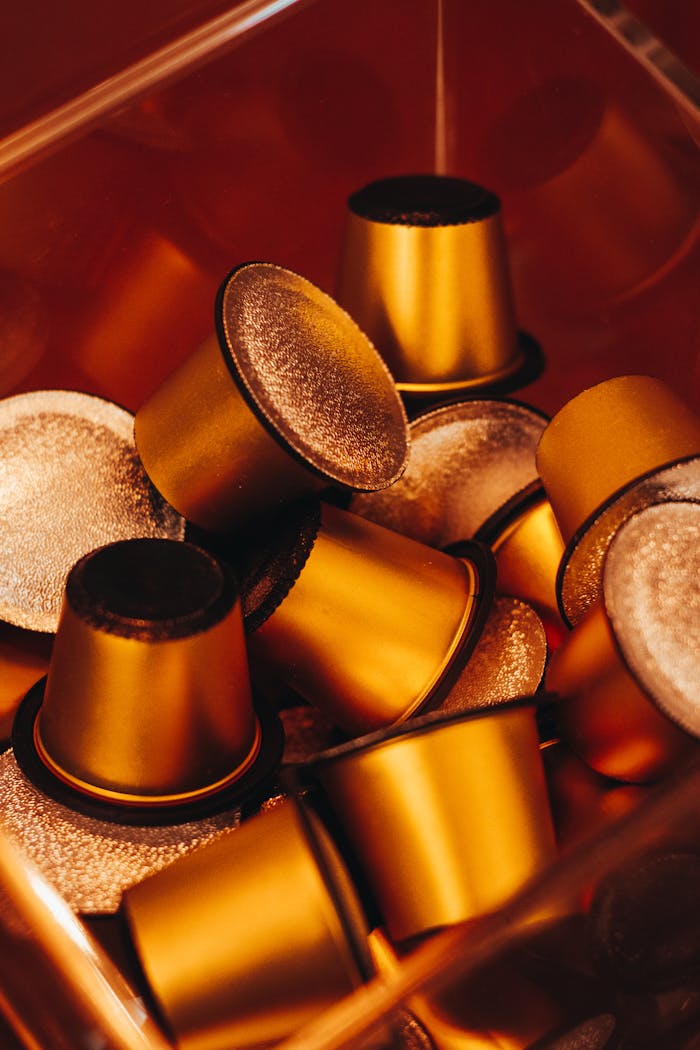 A close-up image of golden coffee capsules in a container, perfect for coffee lovers.