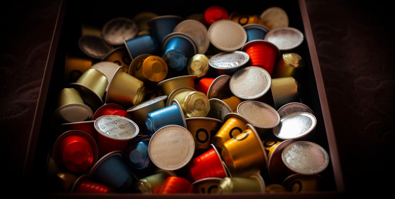 Vibrant collection of coffee capsules overflowing in a dark box, creating a colorful and rich visual.
