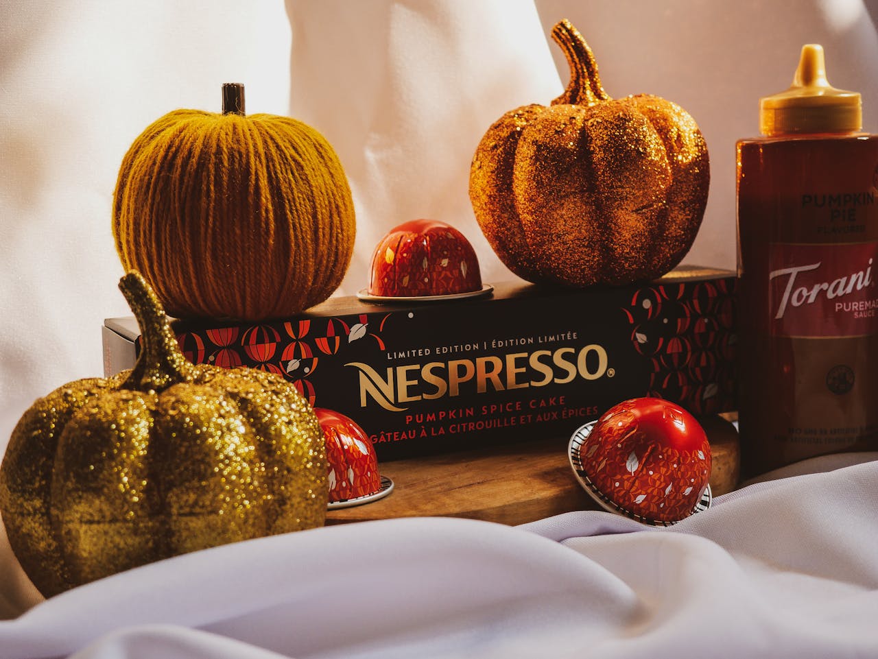 Autumn-themed Nespresso display with pumpkins and coffee pods on a soft, playful background.